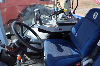 Interiér traktoru s jednoduše koncipovaným ovládacím panelem s pevnou pákou a menším monitorem