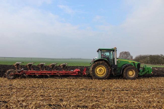 Souprava traktoru John Deere 8430 a již zrenovovaného pluhu Gregoire Besson v průběhu práce na poli.