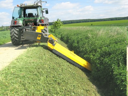 Mulčovač pracující ve šikmém náklonu při údržbě krajnice a příkopu. Díky výkyvnému rameni a robustní konstrukci umožňuje bezpečné a efektivní mulčování i v náročném terénu.