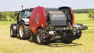 Traktor s červeným lisem a ovíječkou Kverneland FastBale na louce