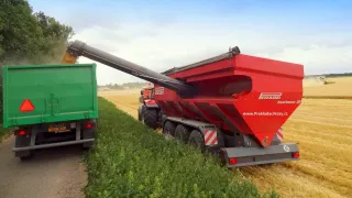 Červený překládací vůz Perard vysypává obilí do zeleného přívěsu