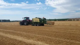 Traktor s lisem při lisování hranatých balíků na poli
