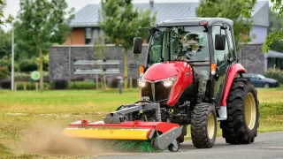 Červený malotraktor Yanmar s čelním žacím strojem při práci.