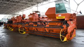 Oranžová sklízecí mlátička Niva SK-5 vystavená pod přístřeškem.
