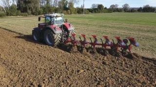 Traktor s červeným pluhem SUKOV při orbě