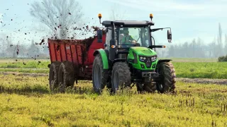Traktor Deutz-Fahr rozmetá hnůj na poli