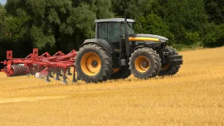 Traktor s kypřičem pracuje na strništi.