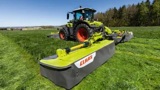 Traktor Claas se žacím strojem Disco na louce.