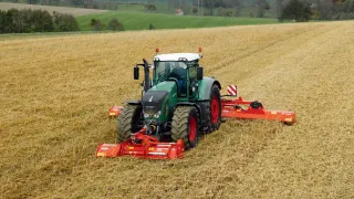 Traktor Fendt s červenými mulčovači Kuhn na poli.