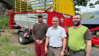 Tři muži před samosběracím vozem Pöttinger