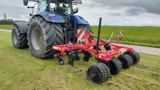 Traktor s červeným strojem SMS Agro na louce