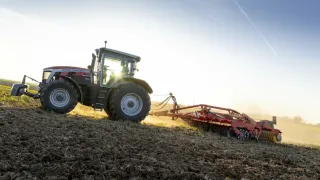 Traktor Massey Ferguson při práci na poli v protisvětle