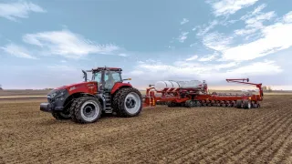 Červený traktor Case IH se secím strojem na poli