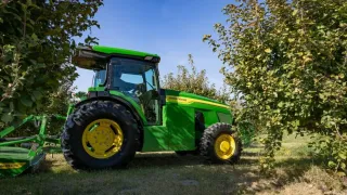 Zelený traktor John Deere v sadu