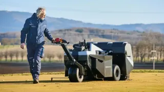 Obsluha stojí u aerifikačního stroje na trávníku