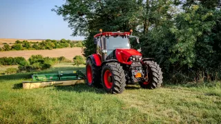 Červený traktor Zetor Řady 6 se žacím strojem na louce