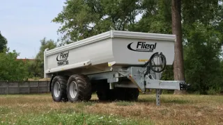 Bílý sklápěcí návěs Fliegl stojící na trávě