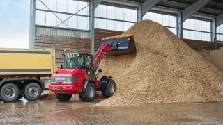 Červený nakladač Weidemann při nakládání materiálu v hale