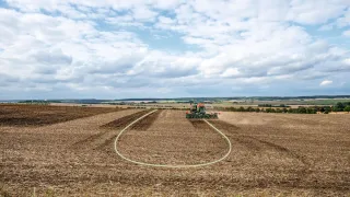 Široký zemědělský pozemek se strojem na obzoru
