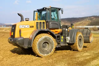 Žlutý kolový nakladač Case 821G XR na hlíně.