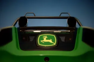 Detail zadní části řezačky John Deere s logem a výfuky