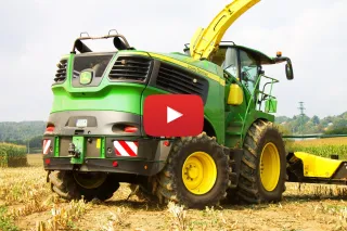 Zelená řezačka John Deere 9800 v kukuřičném poli.