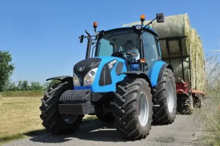 Modrý traktor Landini převážející balíky sena