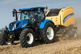 Modrý traktor New Holland s lisem na poli