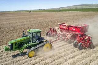 Pásový traktor John Deere se sazečem brambor Spudnik na poli