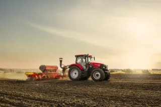 Červený traktor Case IH Maxxum se secím strojem na poli