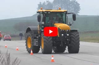 Žlutý traktor JCB Fastrac jede po zkušební dráze.
