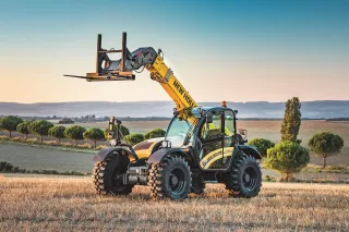 Teleskopický manipulátor New Holland se zvednutými vidlicemi na poli