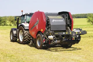 Traktor s červeným lisem a ovíječkou Kverneland FastBale na louce