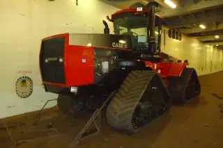 Starší červený pásový traktor Case IH Quadtrac v nákladovém prostoru