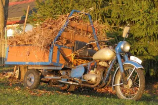 Modrá motocyklová rikša Jawa 250 s nákladem větví