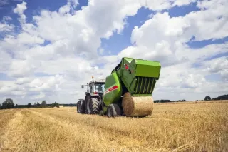 Traktor s lisem SIPMA vyrábí kulatý balík slámy na poli