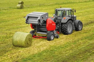 Traktor s lisem UNIA při lisování sena na louce