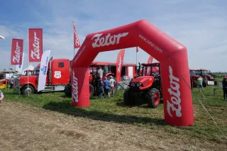 Traktor Zetor pod červeným reklamním obloukem na výstavě