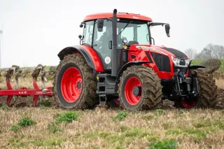 Červený traktor Zetor Crystal s pluhem na poli