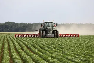 Traktor s červeným kultivátorem Horsch na poli