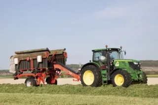 Traktor John Deere s pásovým shrnovačem Kuhn na louce