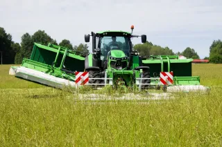 Traktor Deutz-Fahr s čelní a boční sekačkou při sklizni trávy