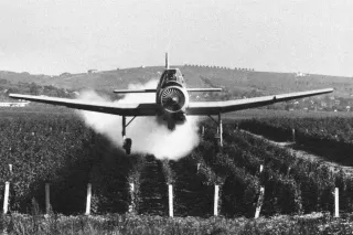 Černobílá fotografie práškovacího letounu Z-37 Čmelák nad polem