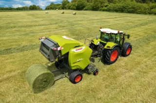 Zelenobílý lis Claas Rollant při práci na louce
