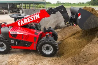 Červený teleskopický manipulátor Faresin nabírá krmivo u stáje
