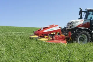 Červený žací stroj Pöttinger Alpha Motion Pro na louce