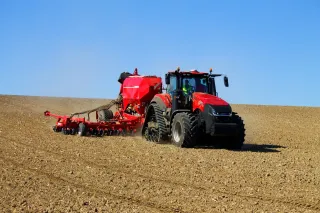 Červený traktor Case IH Magnum se secím strojem na poli
