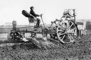 Černobílá historická fotografie řidiče zemědělského stroje