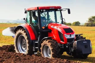 Červený traktor Zetor Forterra s pluhem na poli