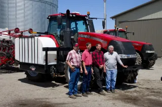 Čtyři farmáři před červenými traktory Case IH na americké farmě
